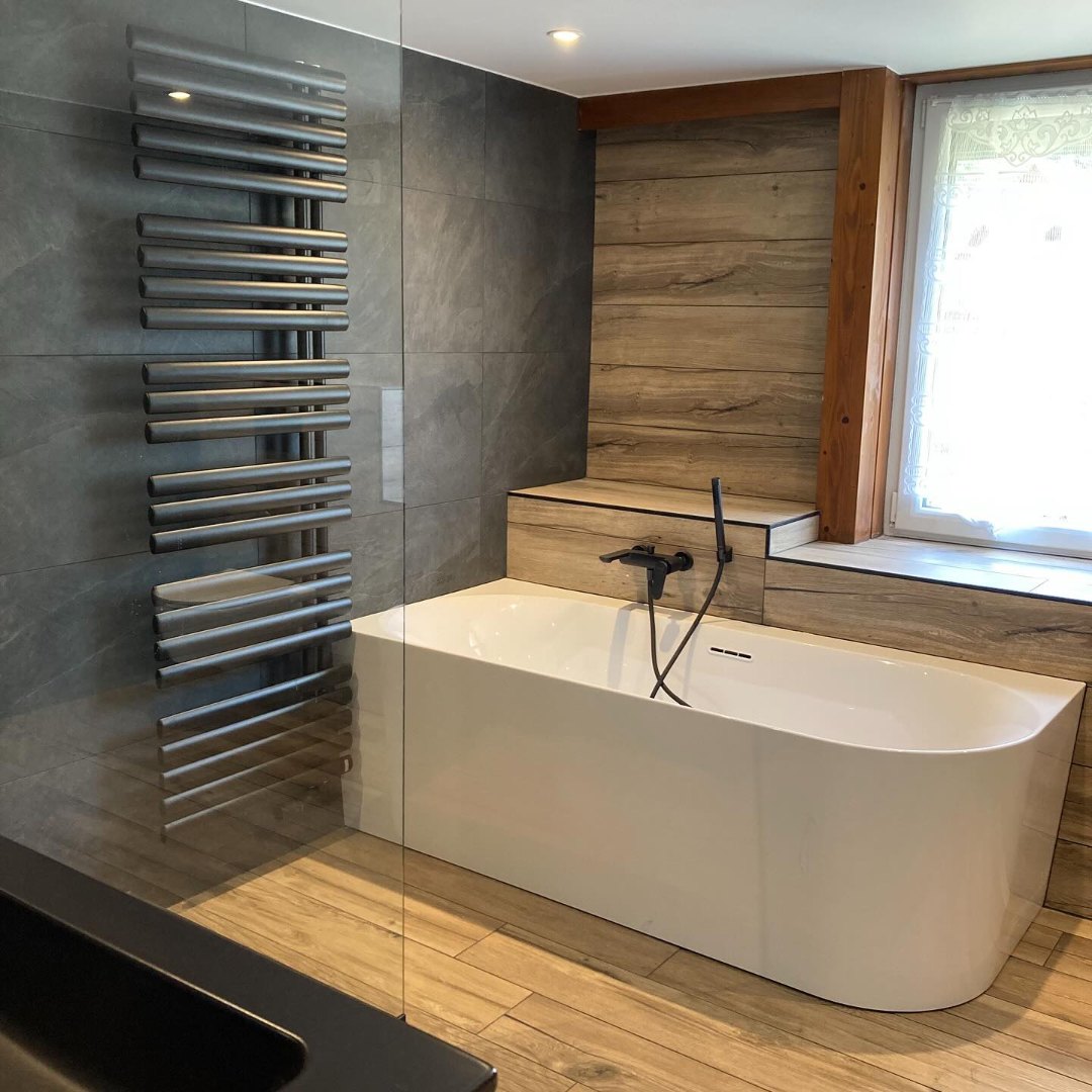 Baignoire îlot et sèche-serviettes dans la salle de bains rénovée