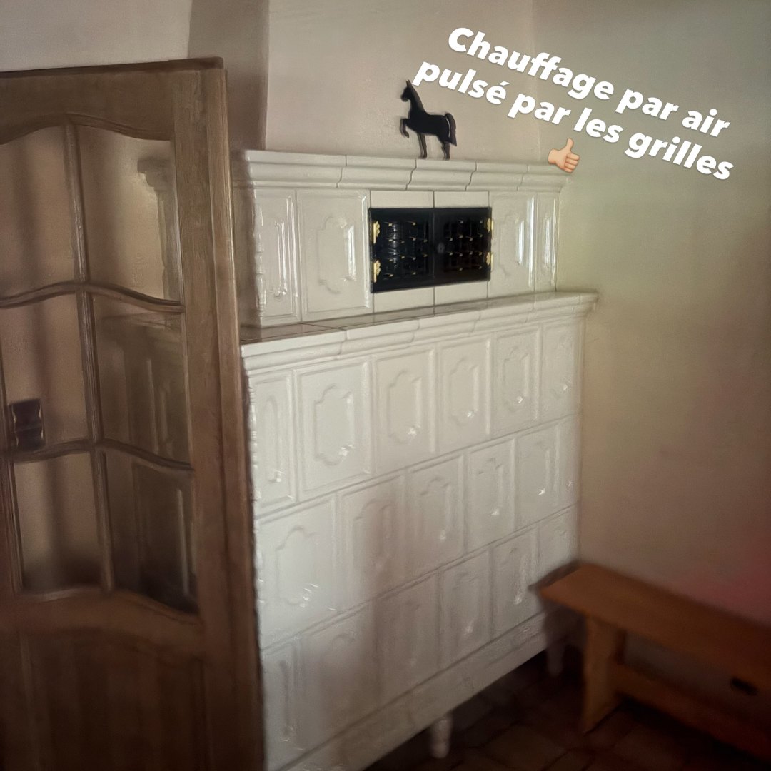 Kachelofen existant qui diffuse l'air chaud par ses grilles